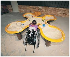 child in wheelchair playing at butterfly sandbox