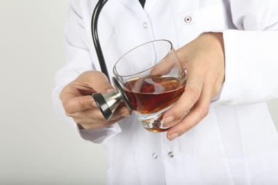 doctor holding an alcoholic drink with stehascope held agains the drink